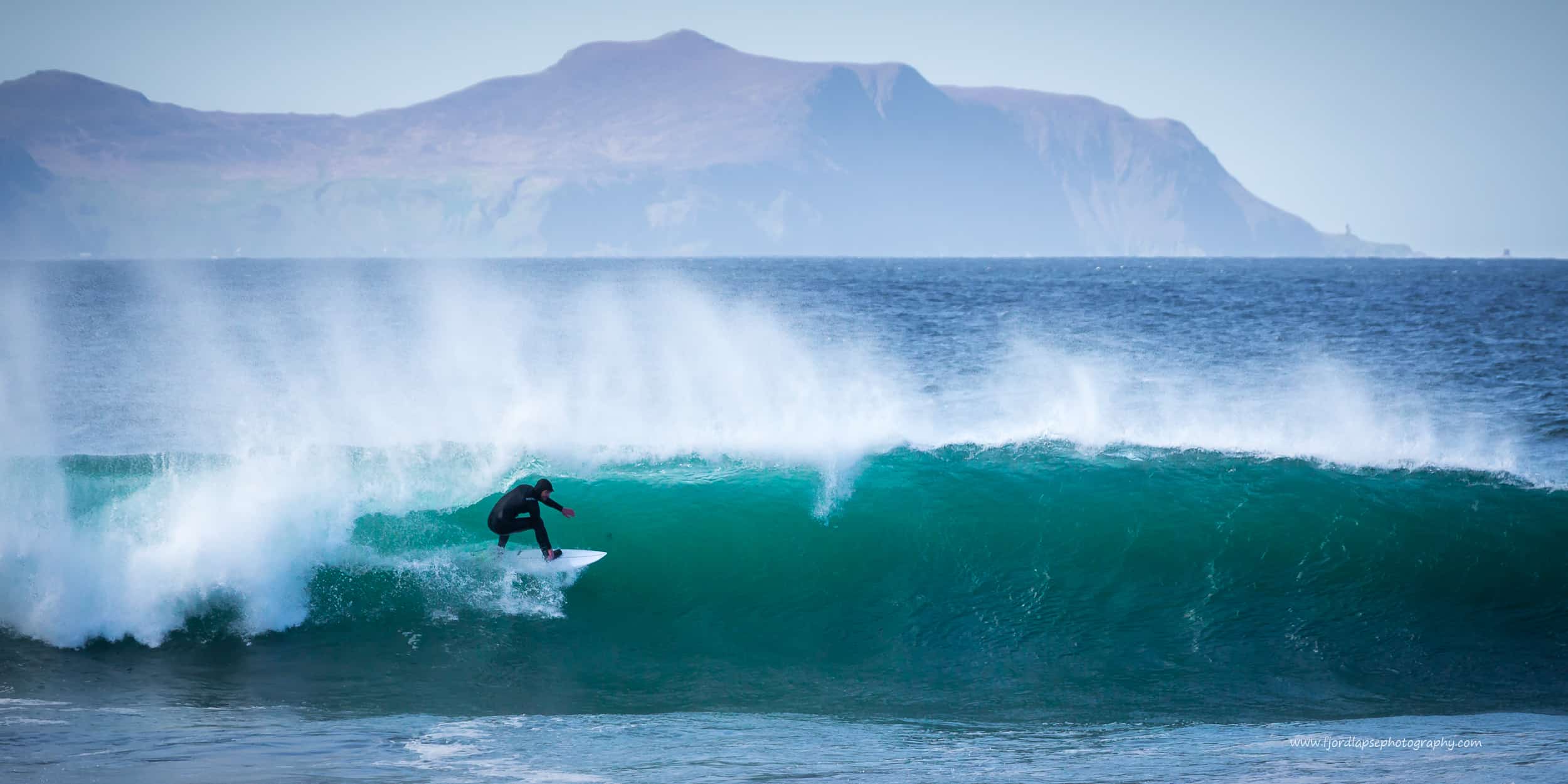 Milde mai! Surfer i bølge på Sunnmøre.