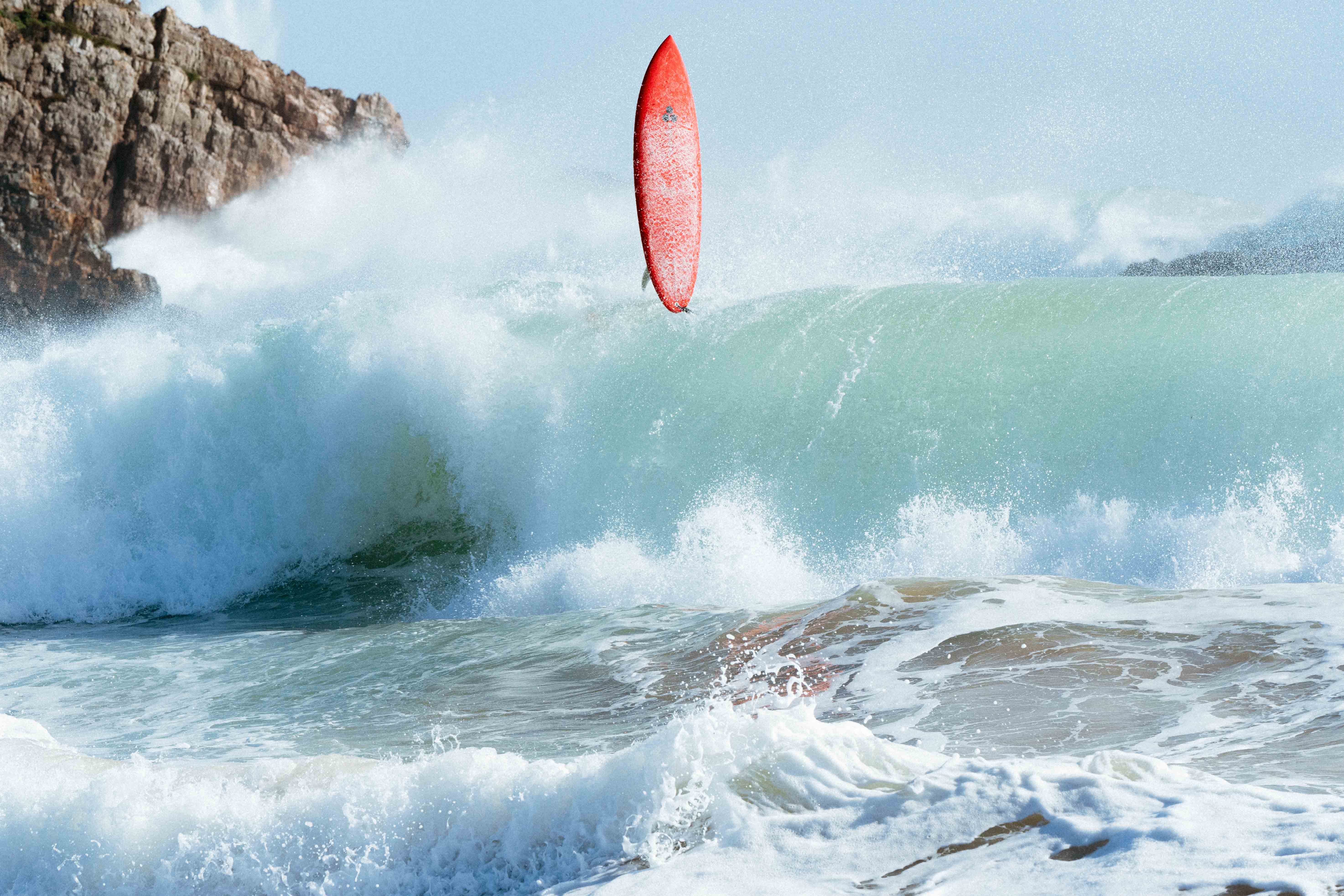 Rødt surfebrett i store bølger i Portugal