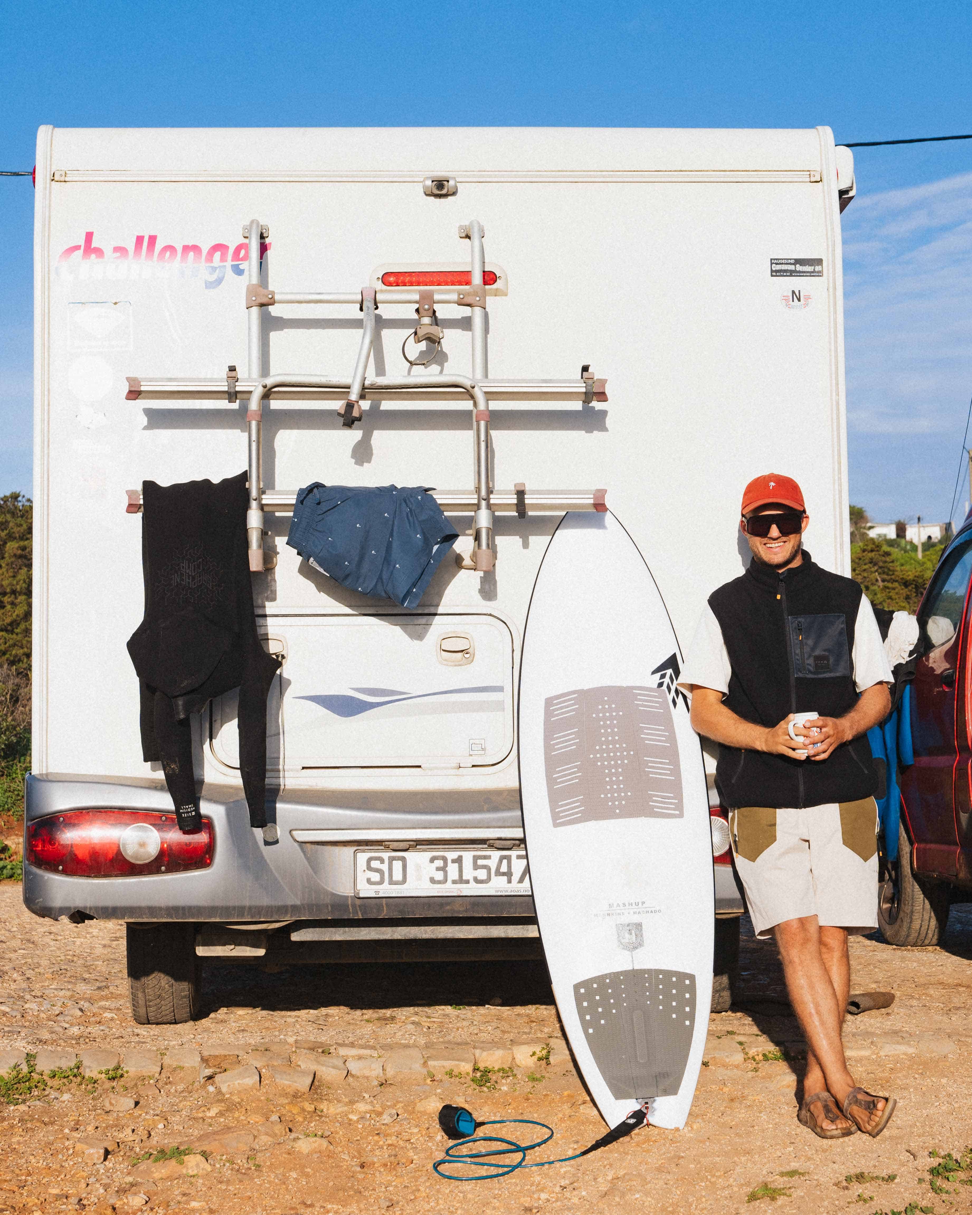Yrjan Olsnes står foran bobilen sin med surfebrett, utstyr i Portugal.