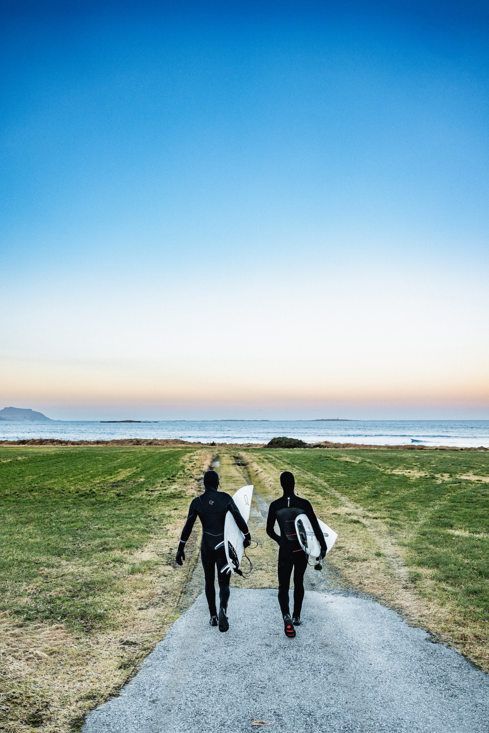 To surfere i våtdrakt går mot havet. Foto: Simon Sjøkvist.