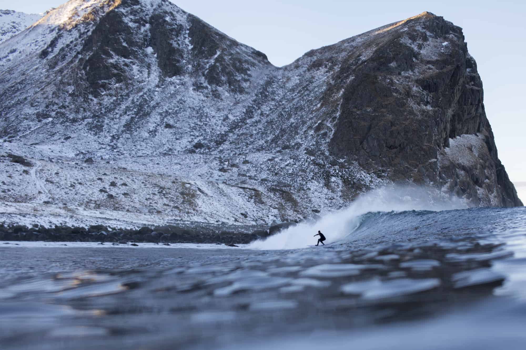Joel Stevenson surfer i Lofoten blant store fjell.