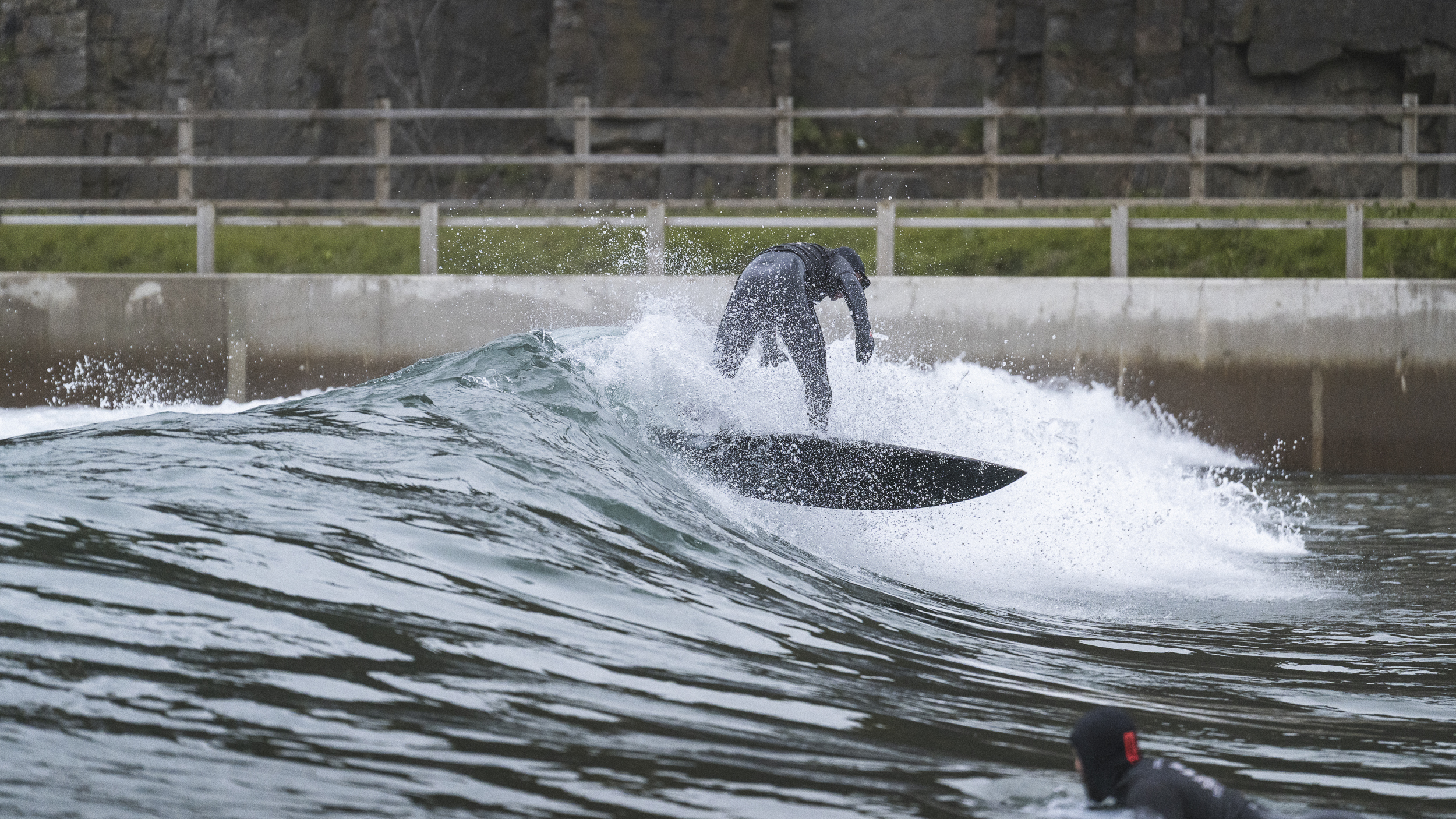 Surfer i våtdrakt skjærer gjennom en kunstig bølge ved Lost Shore Surf Resort i Skottland.